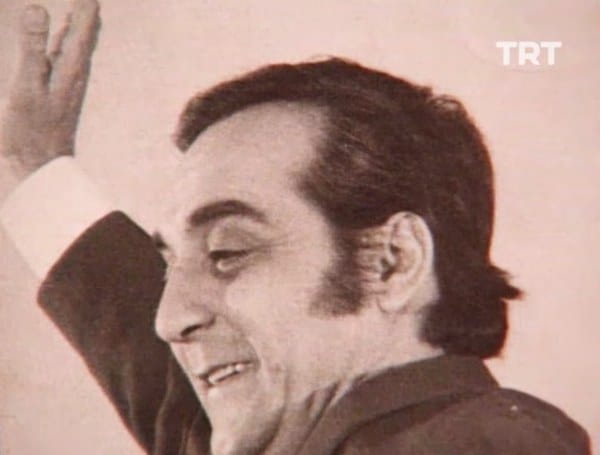Aslen Rum asıllı tulûat ustası Komik-i Şehir Naşit Bey ile Ermeni asıllı tiyatro oyuncusu ve kantocu Amelya Hanım’ın oğlu olarak 15 Ağustos 1928’de İstanbul’da dünyaya geldi. Amelya Hanım'ın annesi zamanının meşhur kantocularından Osmanlı Ermenisi Küçük Virjin, babası ise Osmanlı Rumu, Kemani Yorgo Efendi'dir.